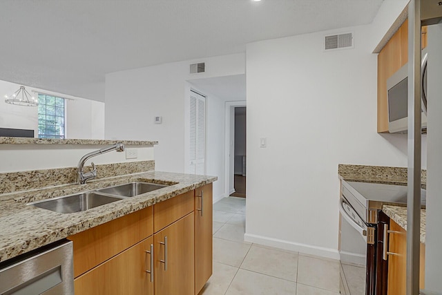 kitchen with sink, appliances with stainless steel finishes, a notable chandelier, light tile patterned flooring, and light stone counters