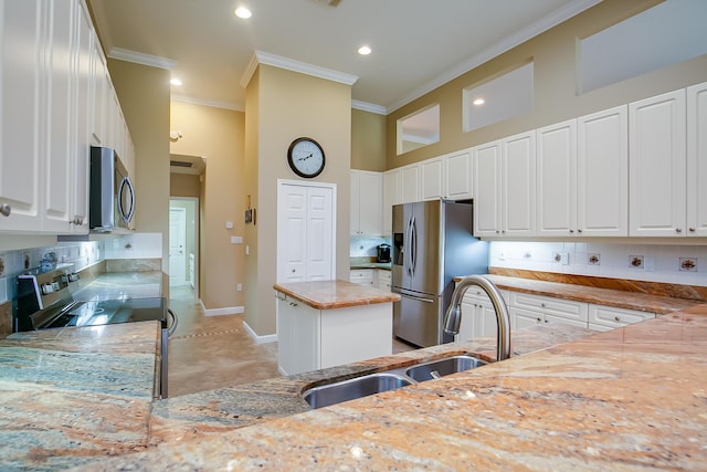 kitchen featuring a high ceiling, white cabinets, a kitchen island, light stone counters, and stainless steel appliances