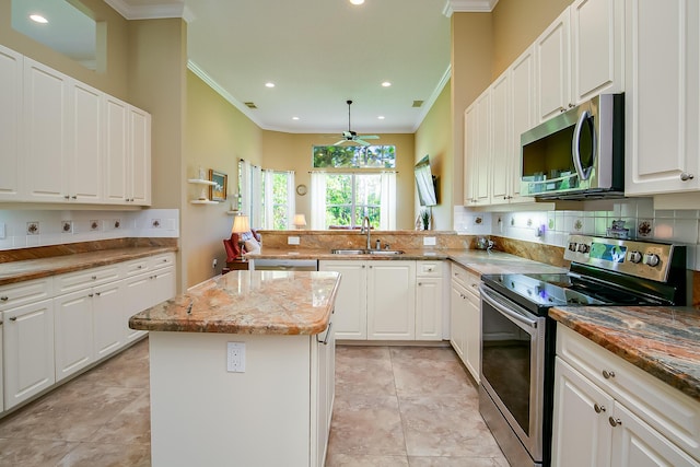 kitchen featuring white cabinets, stainless steel appliances, a kitchen island, and sink