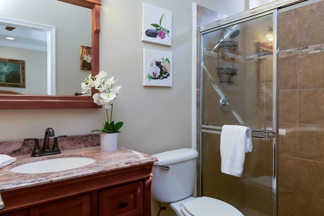 bathroom with a shower with door, vanity, ornamental molding, and toilet