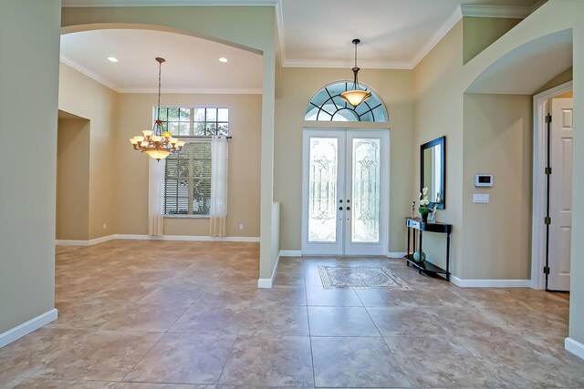 foyer entrance with french doors, ornamental molding, and a notable chandelier