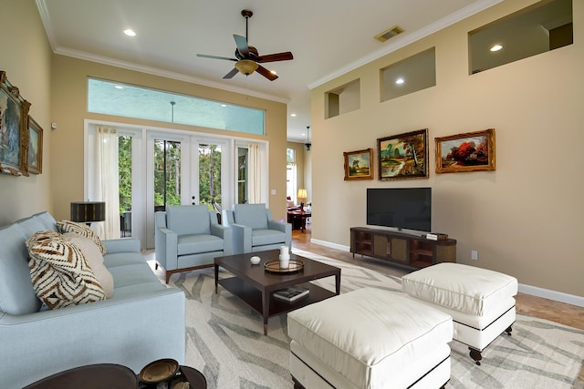 living room featuring french doors, a towering ceiling, ceiling fan, and crown molding