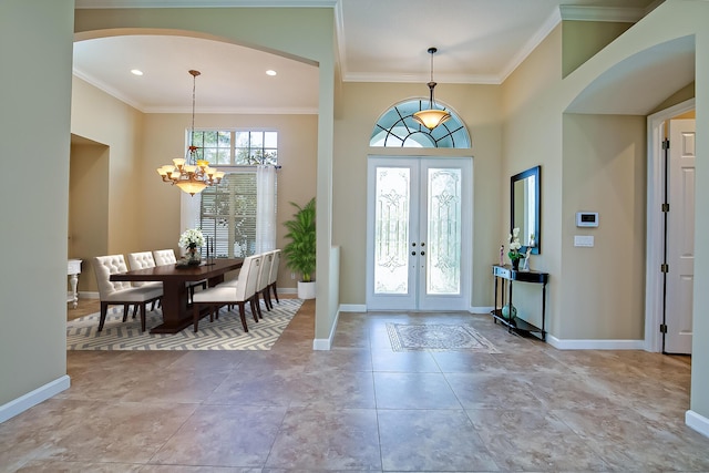 entryway with french doors, ornamental molding, a high ceiling, and a notable chandelier