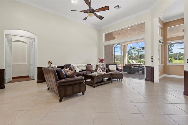 living room with ceiling fan, light tile patterned floors, a high ceiling, and ornamental molding