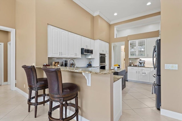 kitchen featuring white cabinetry, light tile patterned floors, stainless steel appliances, and light stone counters