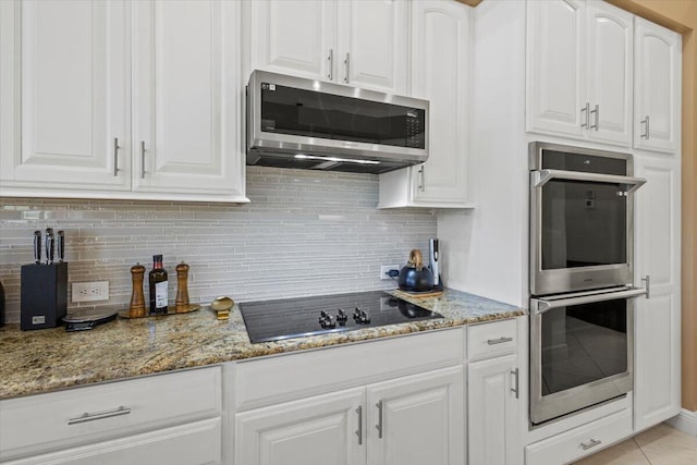 kitchen with white cabinets, light stone counters, stainless steel appliances, and tasteful backsplash