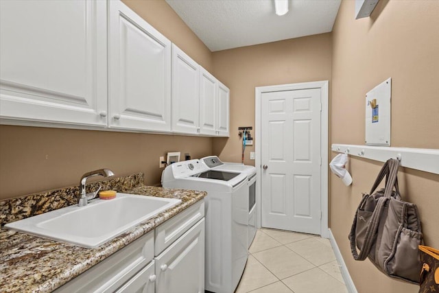 washroom with cabinets, sink, independent washer and dryer, a textured ceiling, and light tile patterned floors