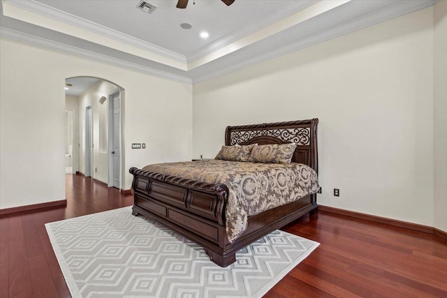 bedroom with hardwood / wood-style floors, a raised ceiling, ceiling fan, and crown molding