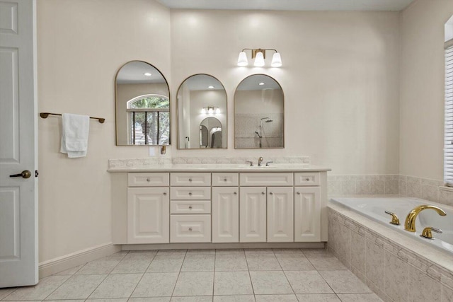 bathroom with tile patterned flooring, vanity, and tiled bath