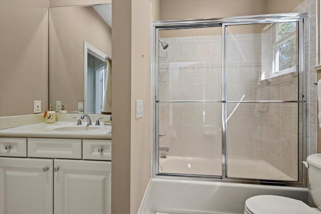 full bathroom featuring combined bath / shower with glass door, vanity, and toilet