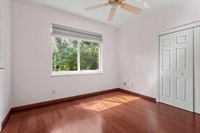 unfurnished bedroom featuring crown molding, ceiling fan, a closet, and dark wood-type flooring