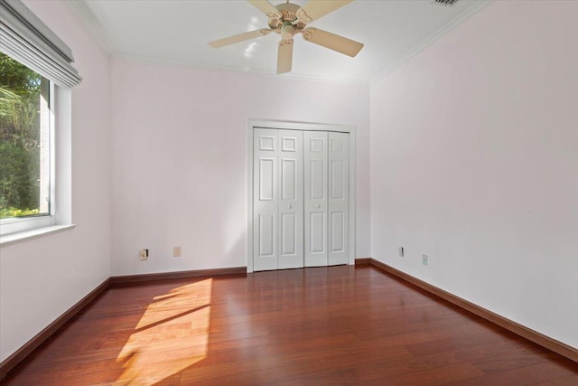 unfurnished bedroom featuring ceiling fan, crown molding, dark wood-type flooring, and a closet