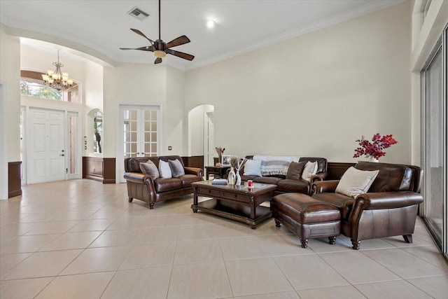 tiled living room with ceiling fan with notable chandelier, a towering ceiling, and ornamental molding