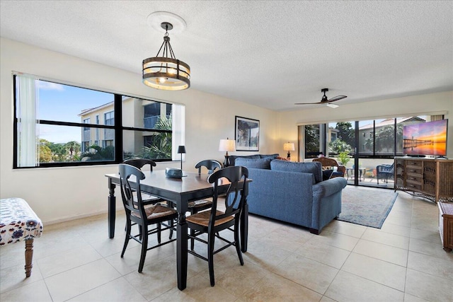 tiled dining area featuring ceiling fan with notable chandelier, plenty of natural light, and a textured ceiling