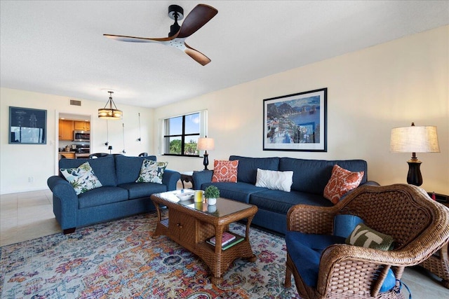 living room featuring ceiling fan and a textured ceiling