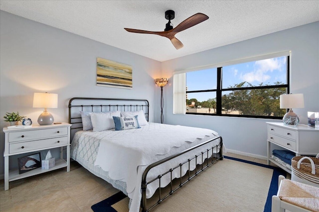 bedroom with ceiling fan, light tile patterned flooring, and a textured ceiling