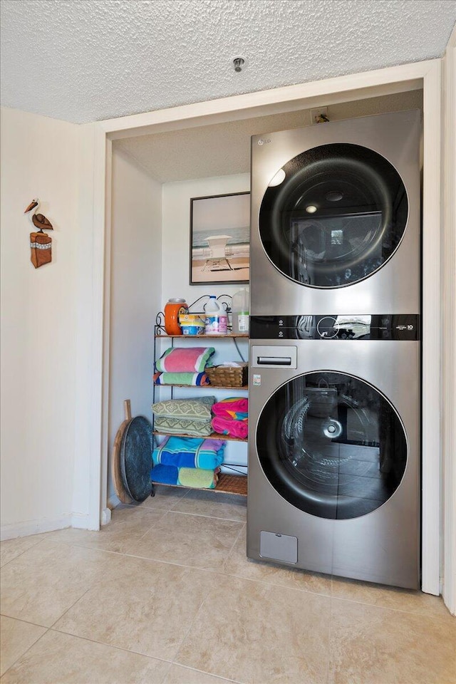 washroom with light tile patterned floors, a textured ceiling, and stacked washing maching and dryer