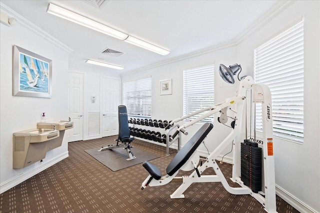 workout room featuring dark colored carpet and crown molding