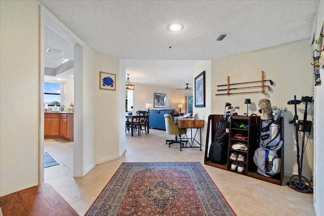 hall with light tile patterned flooring and a textured ceiling