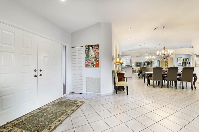 entryway with light tile patterned floors, lofted ceiling, visible vents, an inviting chandelier, and baseboards