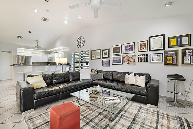 living room featuring lofted ceiling, ceiling fan, and light tile patterned floors