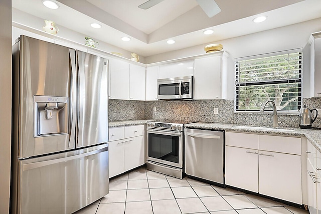 kitchen featuring backsplash, white cabinets, sink, vaulted ceiling, and appliances with stainless steel finishes