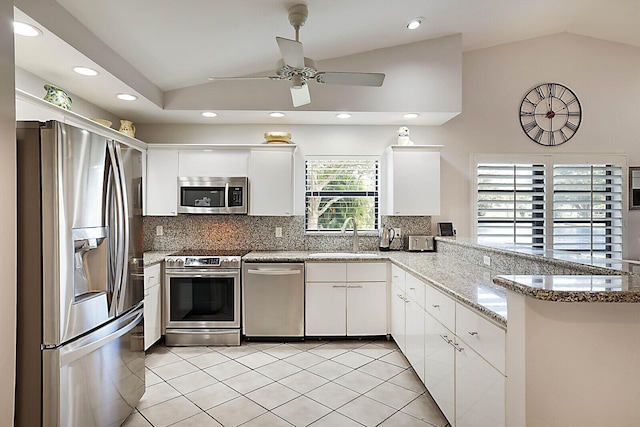 kitchen featuring lofted ceiling, light tile patterned flooring, stainless steel appliances, a peninsula, and a sink