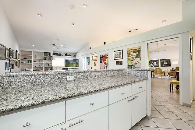 kitchen featuring white cabinetry, light stone countertops, ceiling fan, vaulted ceiling, and light tile patterned floors