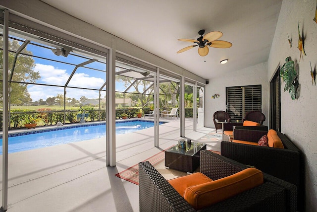 outdoor pool featuring glass enclosure, ceiling fan, outdoor lounge area, and a patio