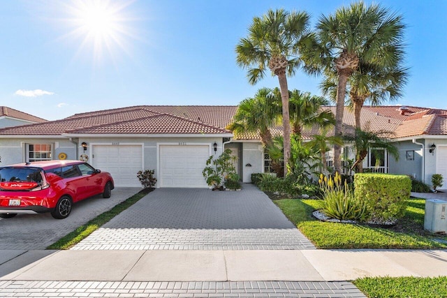 view of front of house with a garage, a tile roof, decorative driveway, and stucco siding