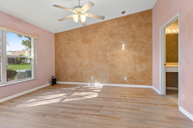 unfurnished room featuring a ceiling fan, light wood-style flooring, and baseboards