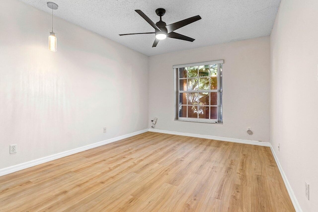 empty room with a textured ceiling, ceiling fan, wood finished floors, and baseboards