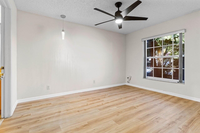 empty room featuring light wood-style flooring, baseboards, ceiling fan, and a textured ceiling