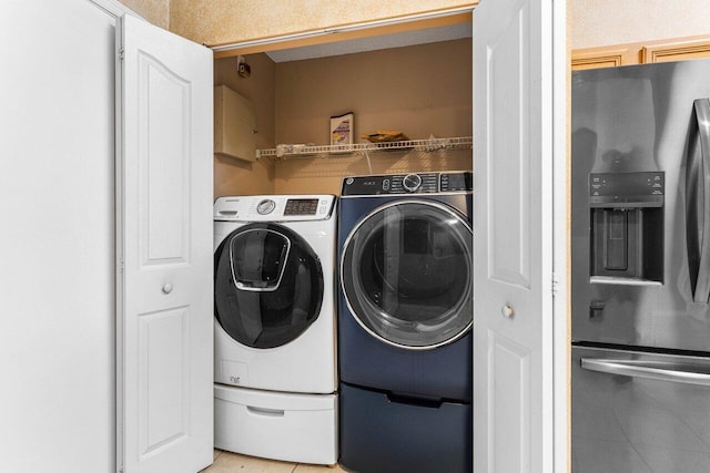 washroom featuring light tile patterned floors, laundry area, and washer and clothes dryer