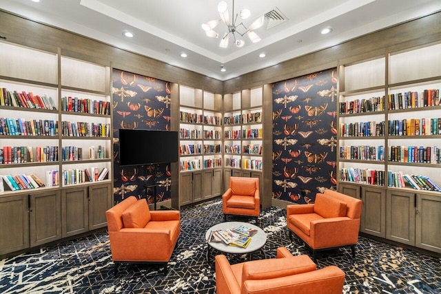 sitting room featuring built in shelves, a notable chandelier, recessed lighting, visible vents, and wall of books