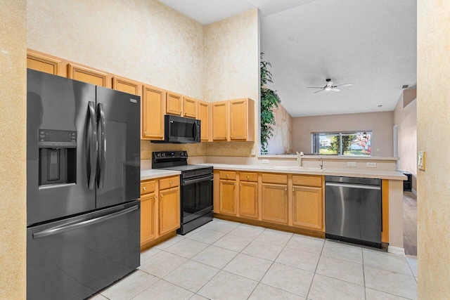 kitchen featuring light tile patterned floors, a peninsula, light countertops, black appliances, and a sink