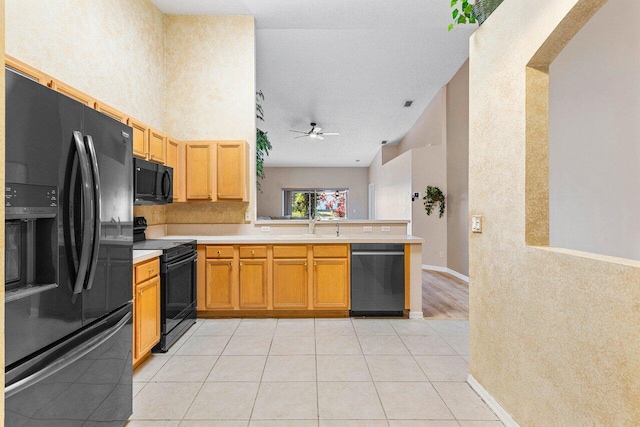 kitchen with a peninsula, black appliances, light countertops, and a ceiling fan