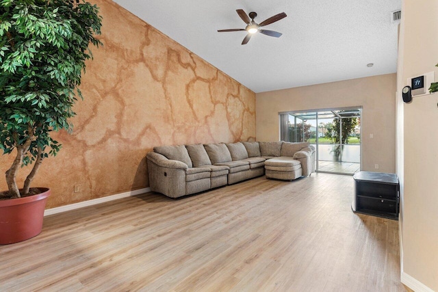 living room with baseboards, ceiling fan, wood finished floors, vaulted ceiling, and a textured ceiling