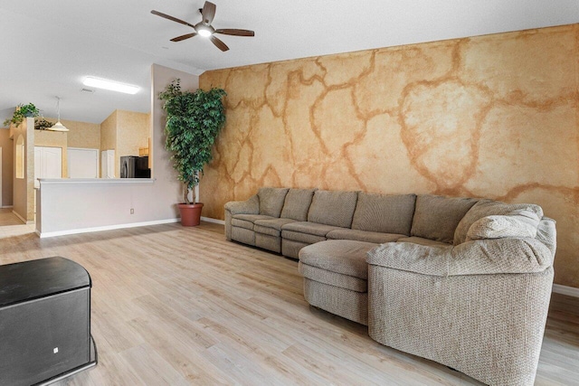 living room featuring lofted ceiling, ceiling fan, light wood-type flooring, and baseboards