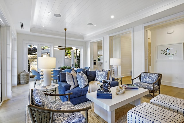 living room with a chandelier, light hardwood / wood-style floors, wood ceiling, and a tray ceiling