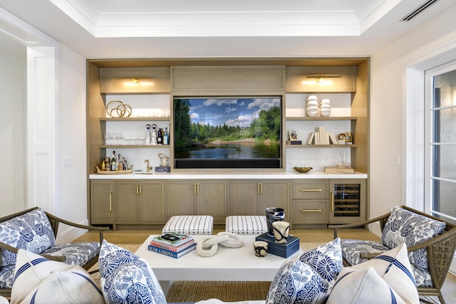 bar featuring a tray ceiling, wine cooler, crown molding, and light wood-type flooring