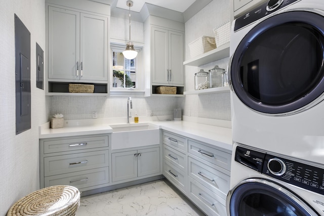 clothes washing area with stacked washer / dryer, sink, cabinets, and electric panel