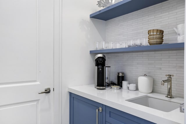 bar with backsplash, blue cabinetry, and sink