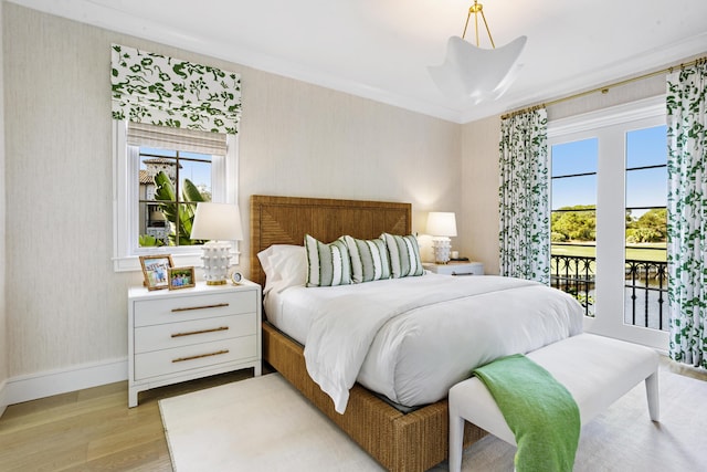 bedroom featuring access to exterior, light hardwood / wood-style floors, and crown molding