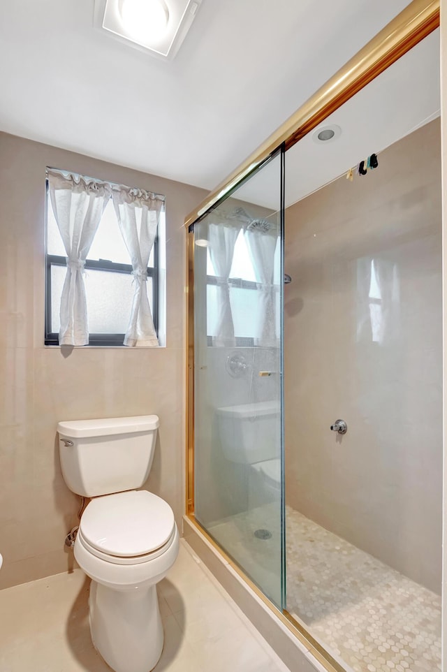 bathroom featuring a shower with door, tile patterned flooring, and toilet