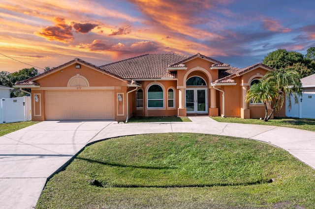 mediterranean / spanish-style house with a garage, a yard, and french doors