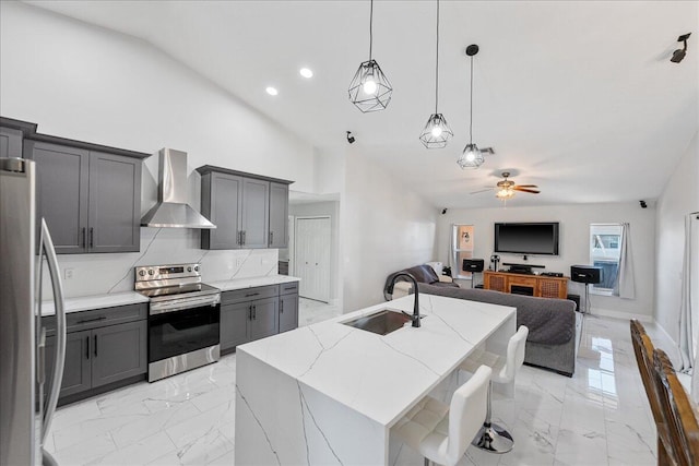 kitchen featuring a kitchen island with sink, sink, wall chimney exhaust hood, light stone countertops, and stainless steel appliances