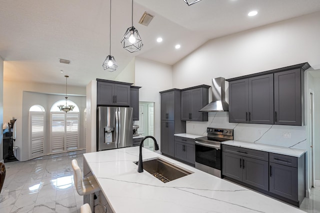 kitchen featuring appliances with stainless steel finishes, backsplash, wall chimney exhaust hood, sink, and hanging light fixtures