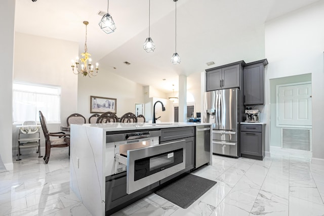 kitchen with pendant lighting, gray cabinetry, a center island with sink, sink, and stainless steel appliances