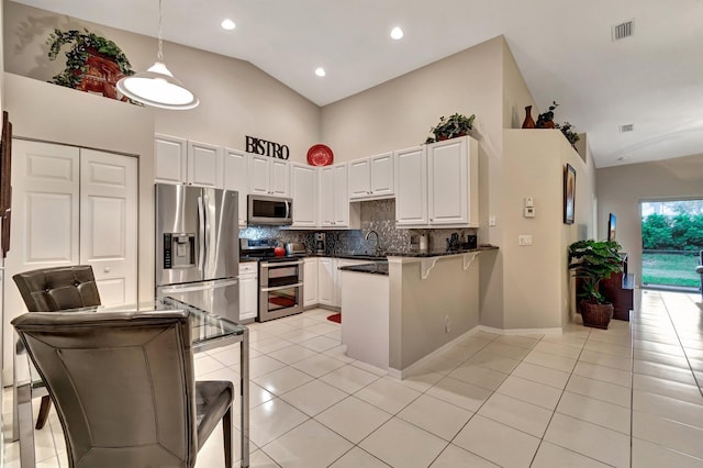 kitchen featuring white cabinetry, high vaulted ceiling, hanging light fixtures, appliances with stainless steel finishes, and kitchen peninsula